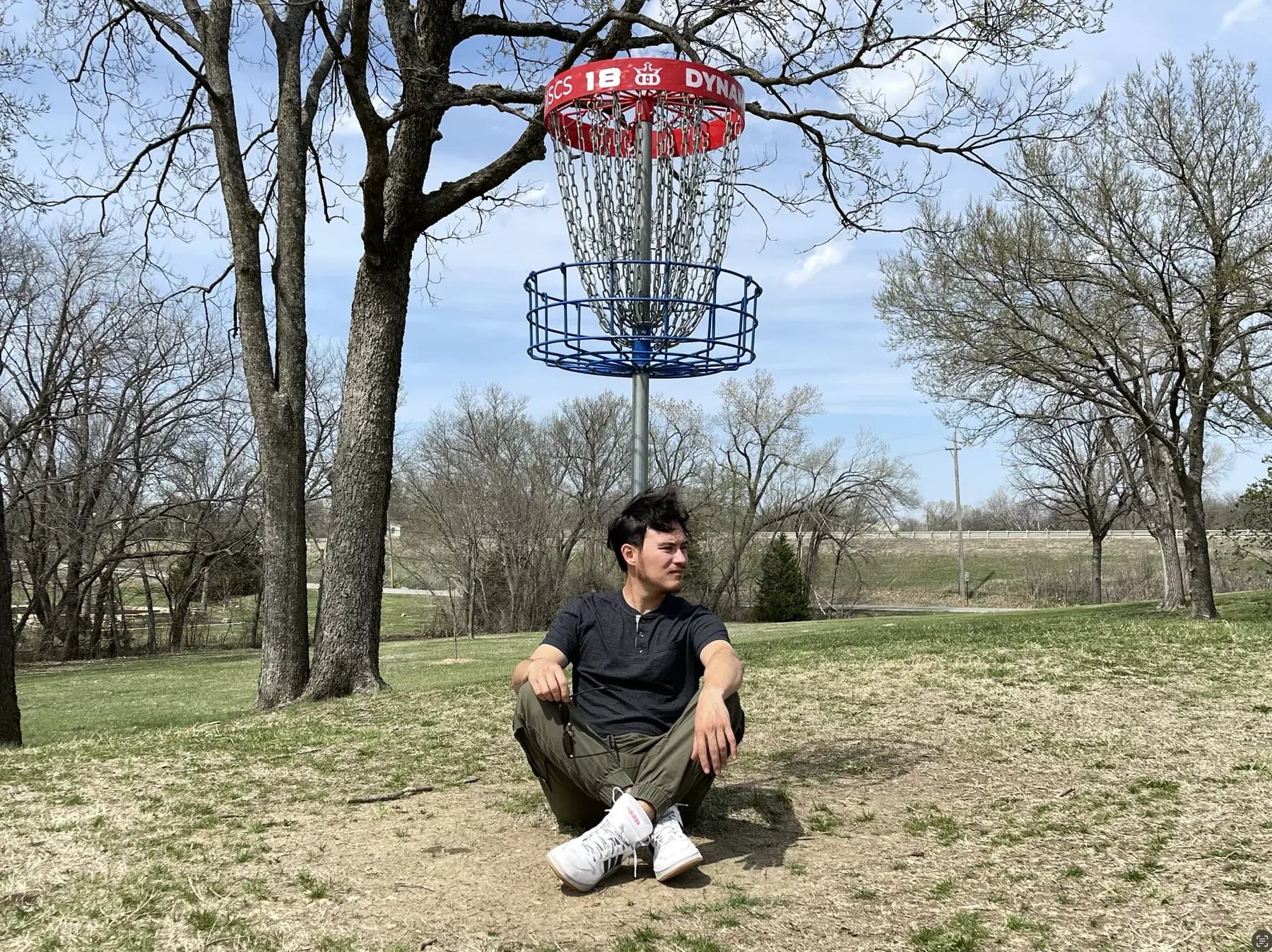 Fabián Oloarte seated outdoors beneath a Dynamic Discs basket.